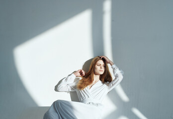 Naklejka premium Romantic woman in a sundress indoors and falling light on the wall