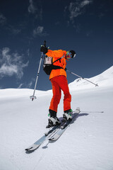 Wide angle young male athlete skier in a ski tour on skis on the background of snow-capped mountains on a sunny day. Skitour professional