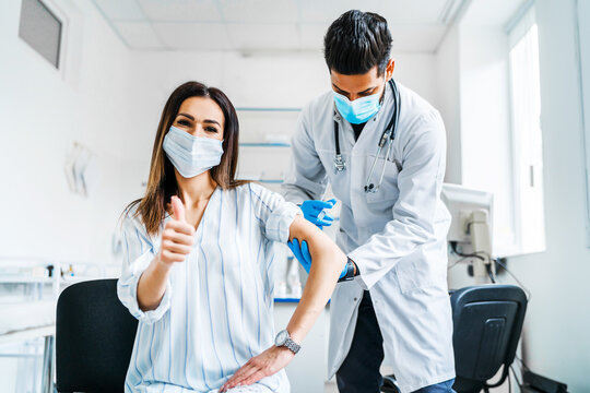 Vaccination of the patient, the doctor in a protective mask injects the vaccine into the patient's hand, it shows the camera okay, vaccination against coronavirus, health and safety