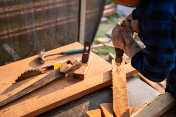 Carpenter drills wood a hole with an electrical drill.