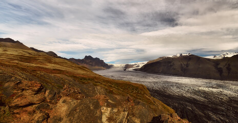 Panoramic photo of a glacier in a valley among the rocks. Iceland.