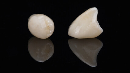 Fototapeta na wymiar two dental ceramic crowns on black glass with reflection