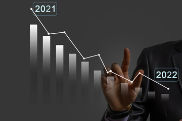 Businessman's hand holds a stock graph display in a visual screen. It shows signs of falling stocks in 2021 with a chart indicator. Concepts of financial interest rates and mortgage rates.
