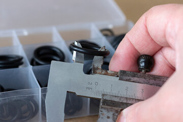 Measuring the diameter of the rubber O-ring with a caliper. An old measuring tool and a set of...