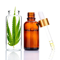Green cannabis leaves with essential oil bottles and dropper oil  reflection isolated on white background. Marijuana hemp ..