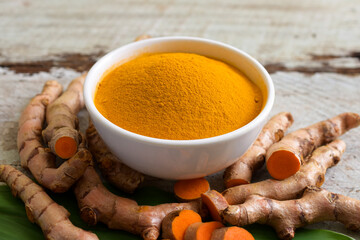 Turmeric (curcumin) powder in a white bowl and turmeric on a wooden table,For cooking,Natural fabric dye.