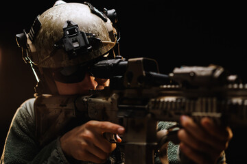 US special forces soldier looking at the aim ready to shoot against black dark background