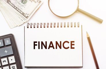 FINANCE - text written on a notebook with office background.