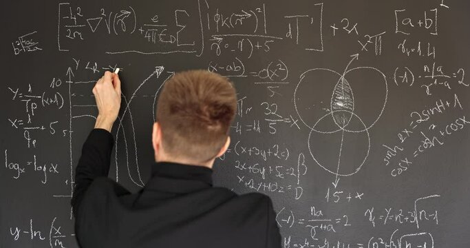 Teacher writing formulas on chalk board