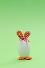 Easter egg with orange bunny ears. Minimal holiday concept on green background.