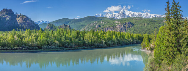 A panoramic view of the river with a calm flow in the Altai mountains. Reflection in the water, sunny day.
