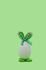 Easter egg with green bunny ears. Minimal holiday concept on green background.