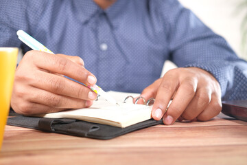 Close up of man hand writing on notepad.