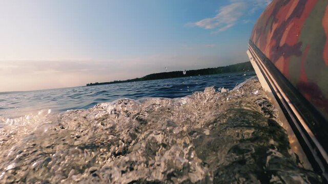 Motor boat traveling. Speed riding. River trip. Close nature. Rubber ship going fast on water surface creating waves foam sunlight flacks reflection blue sky horizon blur.
