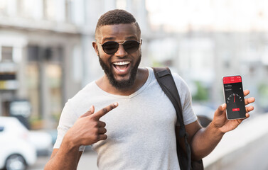 Online smart payment technology. Black guy pointing at smartphone with mobile app for contactless fuel purchase outdoor
