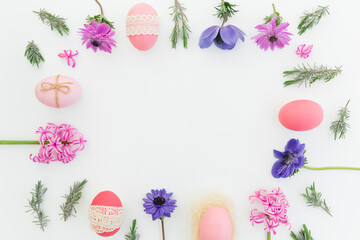 Ester frame made of eggs, spring flowers and leaves of lavender on white background. Flat lay - obrazy, fototapety, plakaty