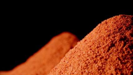 Red pepper powder in a heap on a black background