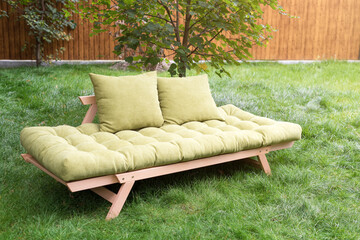 Green sofa in the yard outdoors. Outdoor furniture in green garden patio.