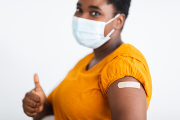 Female Showing Vaccinated Arm And Thumbs-Up Approving Covid-19 Vaccine, Studio