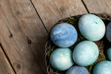Blue Easter eggs in a wicker basket on an antique wooden table