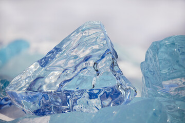 A large transparent ice floe stands vertically on Lake Baikal