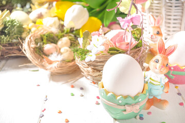 Happy easter concept with nests decoration, colorful eggs, bunny rabbits and Spring Flowers. Greeting card on sunny wooden background
