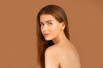 Obraz premium Feminine nude woman with silky skin and long straight hair posing on brown studio background