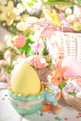 Happy easter concept with nests decoration, colorful eggs, bunny rabbits and Spring Flowers. Greeting card on sunny wooden background