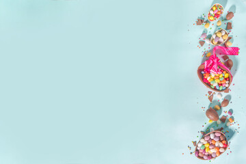 Various Easter Colorful Sweets and Chocolate Eggs flatlay on light blue background top view copy space