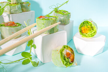 Mediterranean, nordic and keto diet concept. Sushi without rice, diet food with seafood, vegetables. Trendy asian sushi-styled Spring rolls on blue modern background