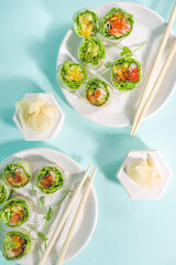 Fototapeta na wymiar Mediterranean, nordic and keto diet concept. Sushi without rice, diet food with seafood, vegetables. Trendy asian sushi-styled Spring rolls on blue modern background