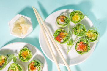 Mediterranean, nordic and keto diet concept. Sushi without rice, diet food with seafood, vegetables. Trendy asian sushi-styled Spring rolls on blue modern background