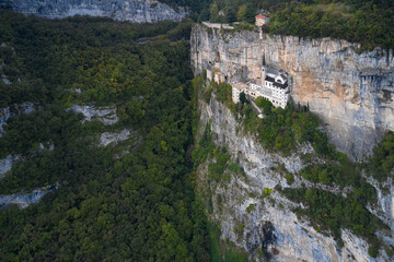 Fototapeta na wymiar The unique Sanctuary Madonna della Corona church in the rock. Italian church at high altitude in the Alps. Aerial view of the church on the sheer cliff. The sanctuary is high in the mountains of Italy