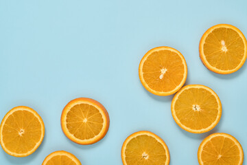 Orange citrus pattern composition. Orange slices with juice are scattered around on a blue background with shadows. Summer or spring concept. Mock up. Top view.