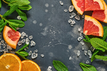 Grapefruit and orange slices, mint, cane sugar, ice, cocktail tubes, juicer or squeezer on black...