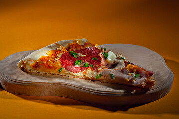 Triangular slice of pizza on a wooden board. Pizza on orange background close up.