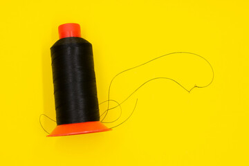 a spool of black thread on a yellow background. Sewing thread. Shoe industry