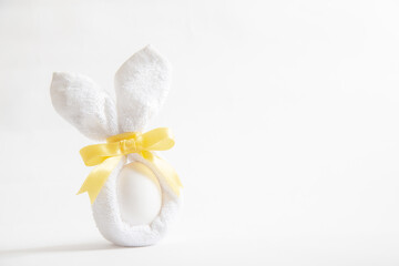 Fototapeta na wymiar Plain white easter egg wrapped with bunny shape cloth. Easter holiday background template with text space.