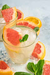 Lemonade drink made from grapefruit, soda water and mint leaves with ice on light blue slate, stone or concrete background. Healthy homemade lemonade or cocktail. Mock up. Top view.