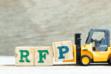 Toy forklift hold letter block P to complete word RFP (Abbreviation of request for proposal) on...
