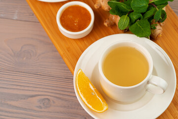 Cup of tea with ginger and mint on wooden table