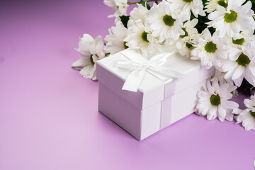 White flowers with a gift box on a purple background.