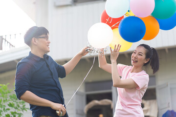Asian Couple playing and tease each other with balloon in the garden