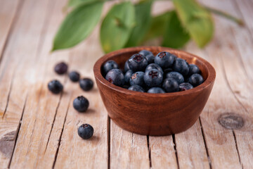 Fototapeta na wymiar Bowl with blueberries on a wooden table, close up