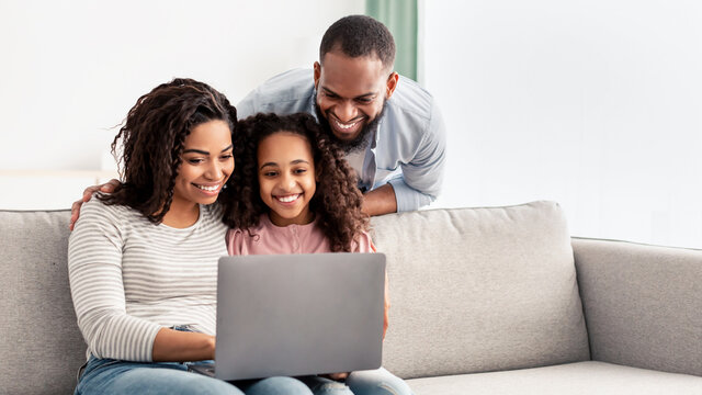 Happy african american family using laptop in living room