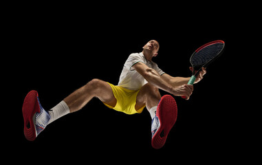 Young caucasian tennis player in action, motion isolated on black background, look from the bottom....