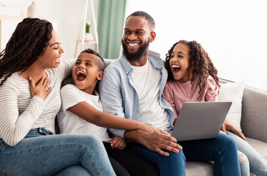 Laughing african american family using laptop in living room