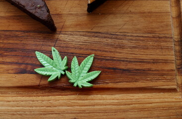 Light green leaves shape fondant on wet brown wood plate, ingredient mix cannabis leaves, Thailand.