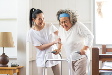 Fototapeta premium Young Asian nurse helping senior woman to walk around the nursing home. Elderly peoples and retirement home service concept.