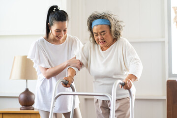 Young Asian nurse helping senior woman to walk around the nursing home. Elderly peoples and retirement home service concept.